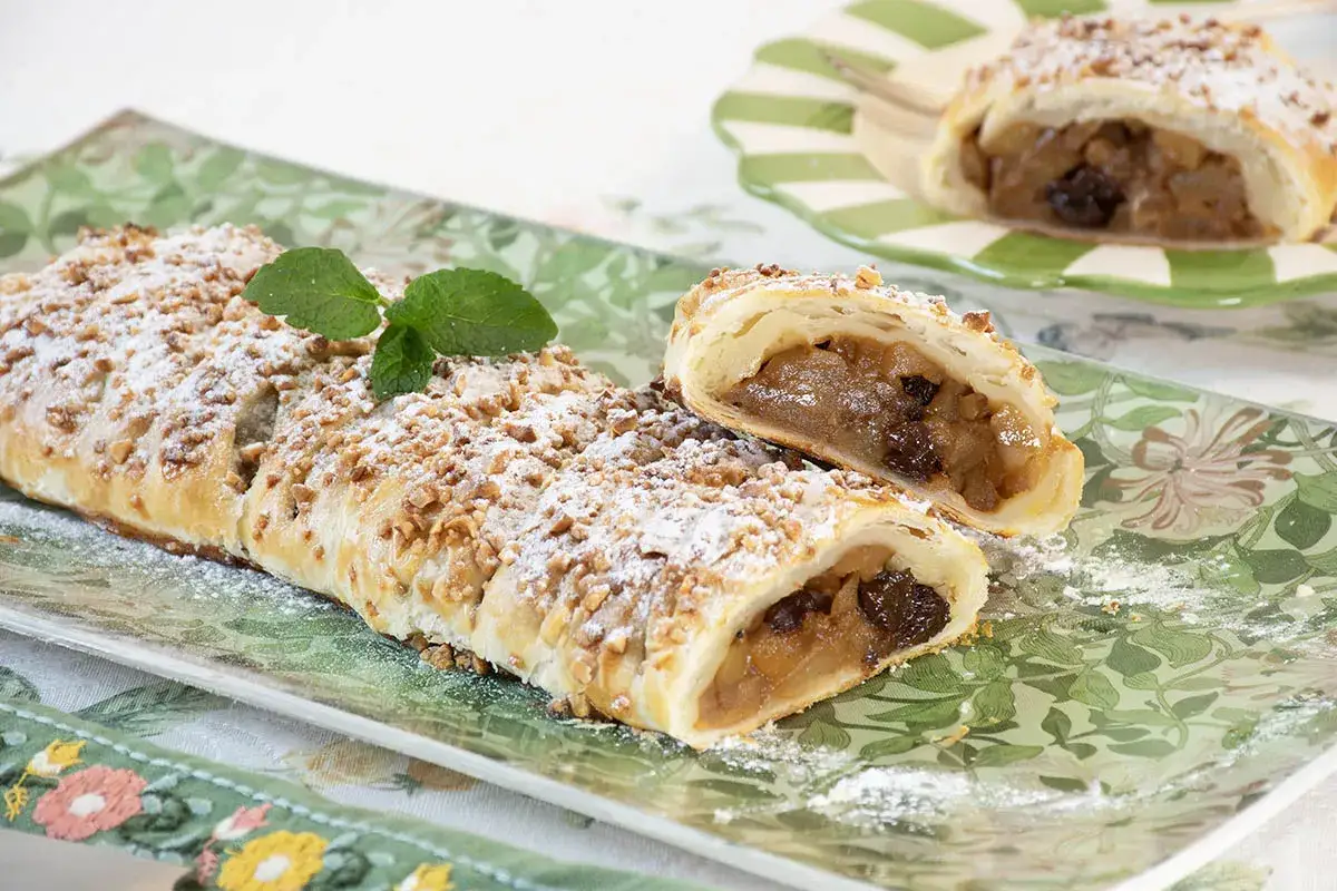 Deliciosa trenza de hojaldre rellena de manzana y pasas, espolvoreada con az&uacute;car glas y nueces picadas.