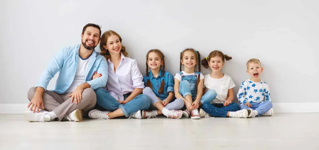 Gl&uuml;ckliche Familie mit vier Kindern sitzt nebeneinander. Ein **Spagat zwischen Kind und neuem Partner** ist hier nicht zu sehen, nur pure Harmonie.