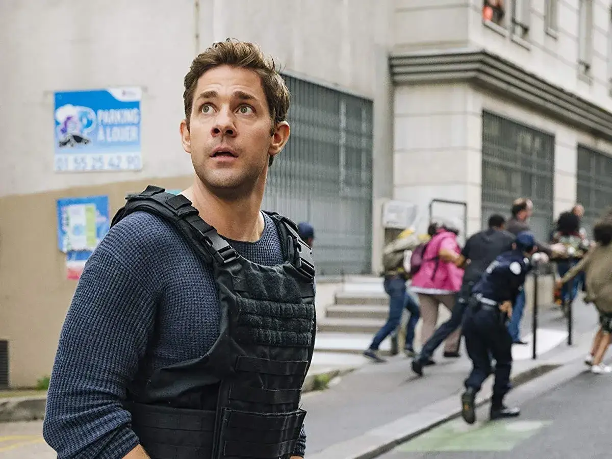 Jack Ryan, i en skyddsv&auml;st, ser oroligt ut &ouml;ver en gata d&auml;r folk springer.