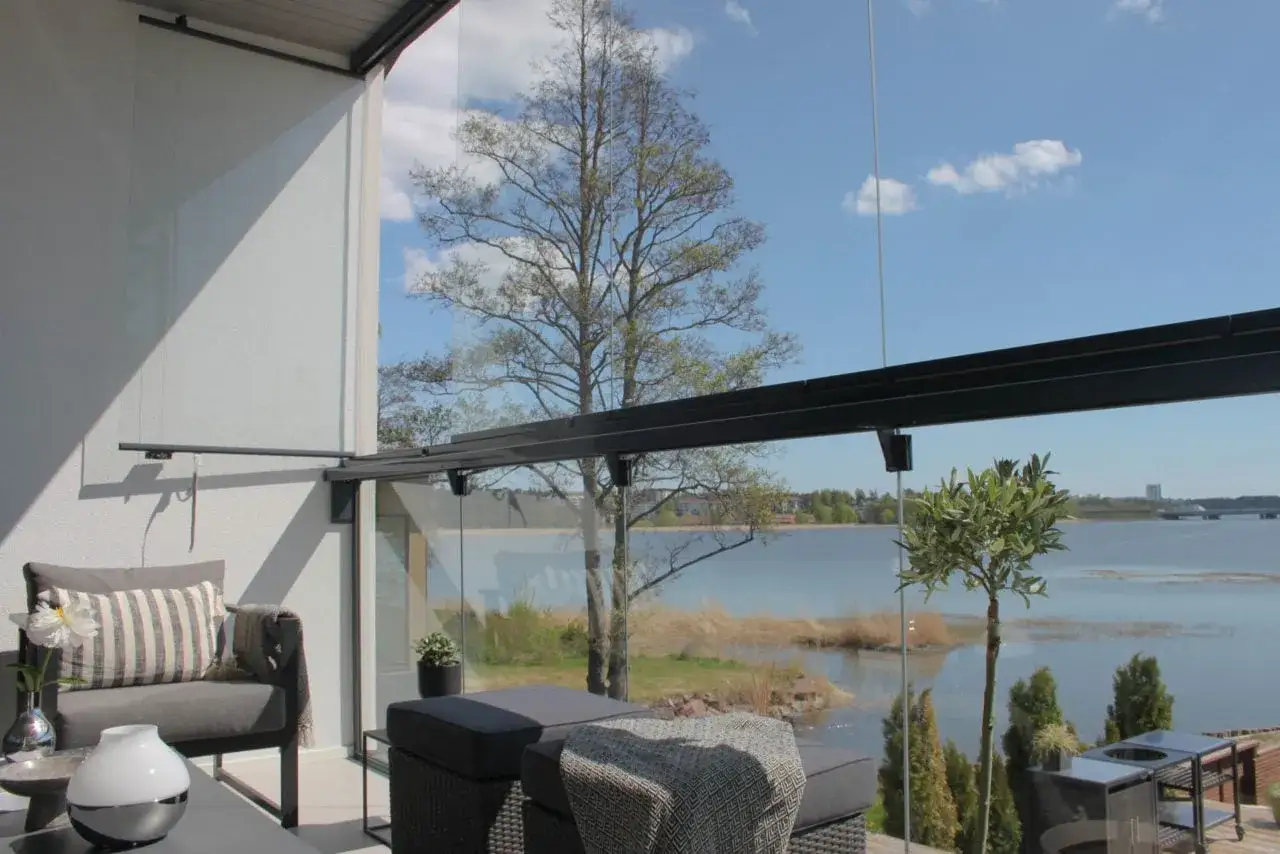 Disfruta de la vista al lago desde estos modernos balcones de cristal, con cómodos muebles de exterior y un árbol frondoso.