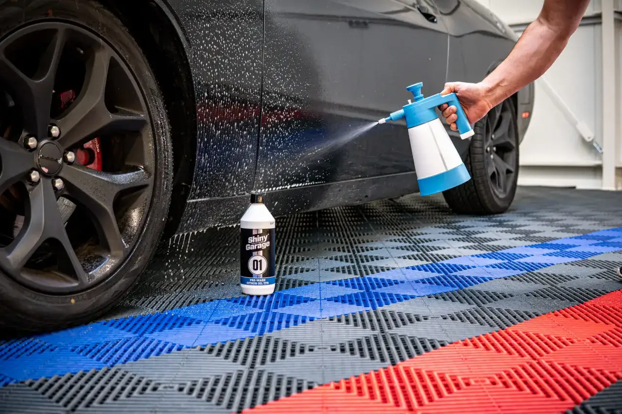 Oprysk pre-wash Shiny Garage na czarnym aucie. Pianownica rozpyla produkt, przygotowując samoch&oacute;d do mycia.