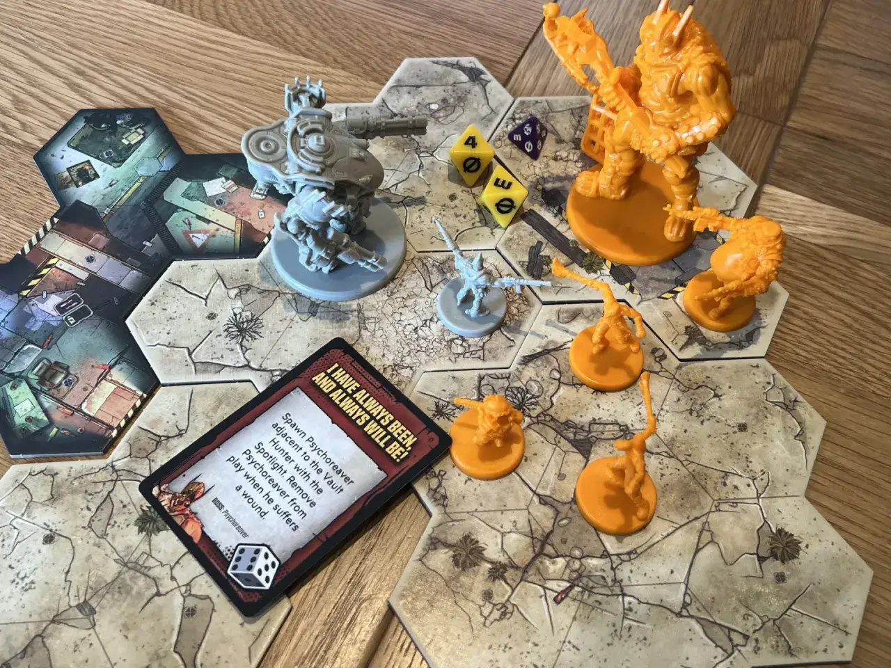 Figuren und Spielbrettteile eines Dungeon Crawler Brettspiels. Ein gro&szlig;er orangefarbener Bossgegner und kleinere orangefarbene Monster stehen auf dem Feld.