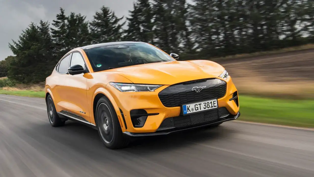 Gul Ford Mustang Mach-E kör på en landsväg. Bilen är i rörelse, vilket ger en känsla av fart. En spännande ford mustang mach-e test.