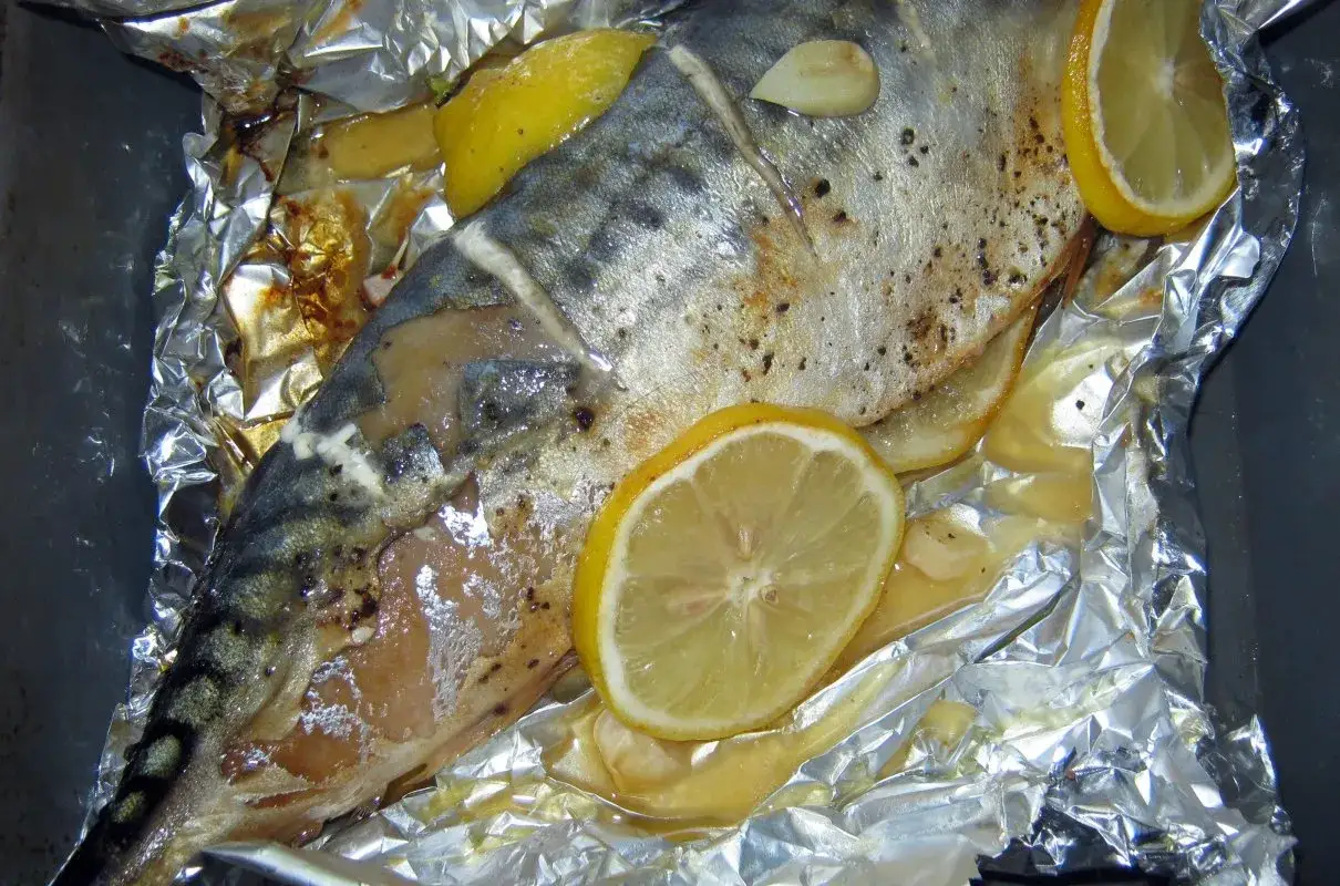 Soczysta makrela pieczona w folii aluminiowej z plasterkami cytryny i czosnkiem. Aromatyczne danie gotowe do podania.