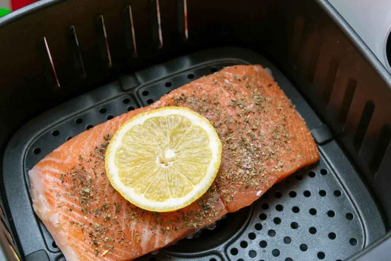 TK Lachs im Airfryer, gewürzt und mit Zitronenscheibe belegt, bereit zur Zubereitung.