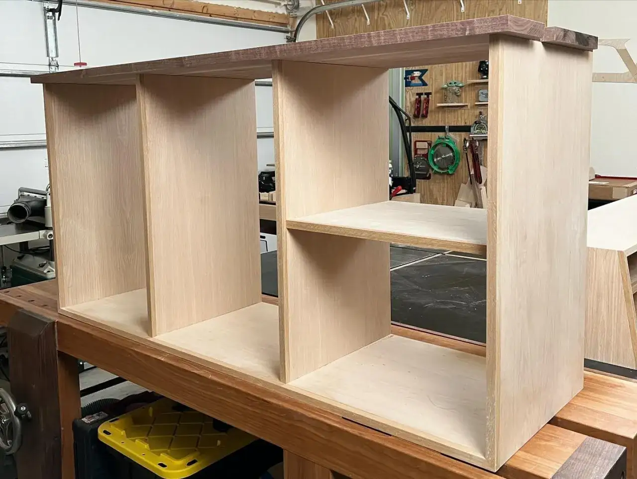 Un meuble de rangement en bois brut, en cours de construction, avec des étagères et des compartiments visibles.