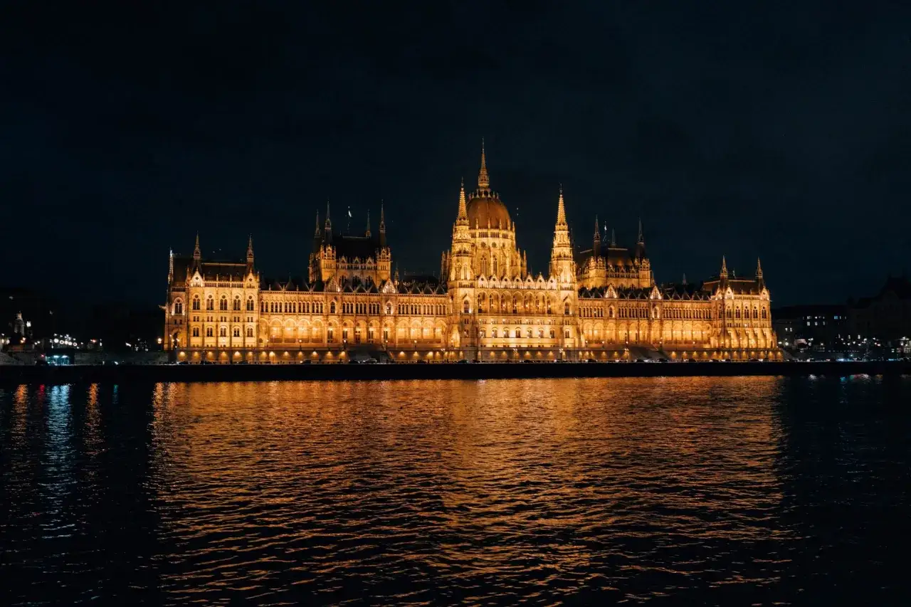 Wspaniały Parlament w Budapeszcie nocą, odbijający się w wodzie. Marzą Ci się loty do Budapesztu?