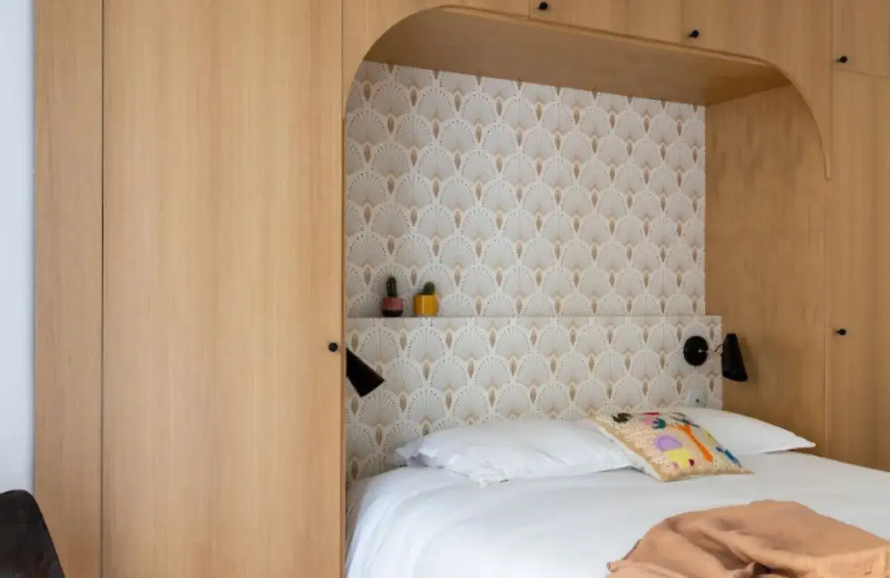 Comment avoir une belle chambre : un lit douillet, une t&ecirc;te de lit originale avec papier peint et des rangements en bois int&eacute;gr&eacute;s.