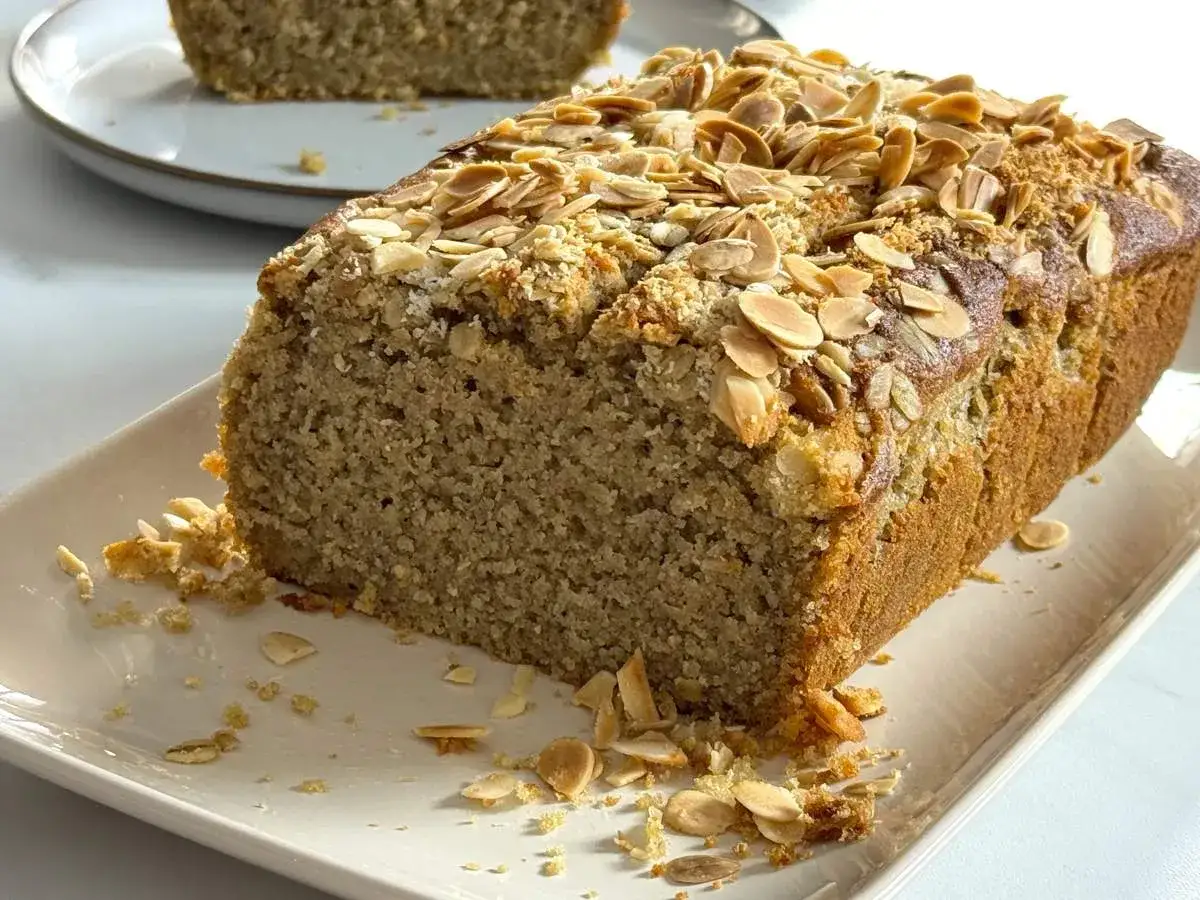 Bizcocho saludable cubierto de almendras laminadas, con migas esparcidas en el plato. &iexcl;Perfecto para un tentempi&eacute; nutritivo!