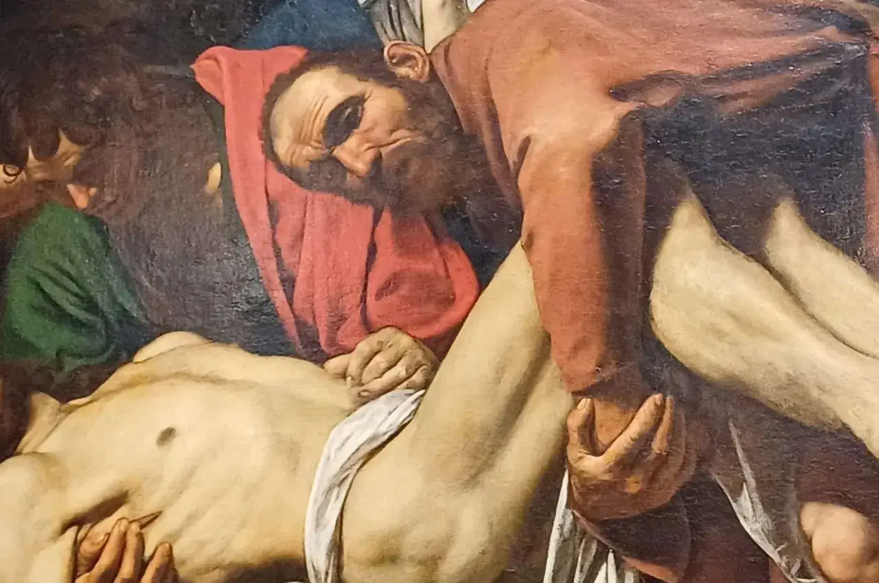 Détail de la mise au tombeau par Caravage : des hommes portent le corps du Christ, le visage marqué par la douleur.