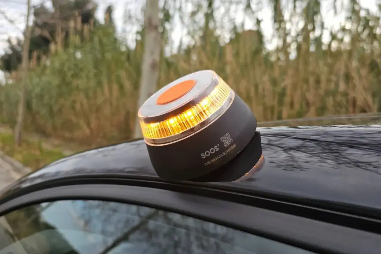 Baliza DGT naranja brillante sobre el techo de un coche negro.