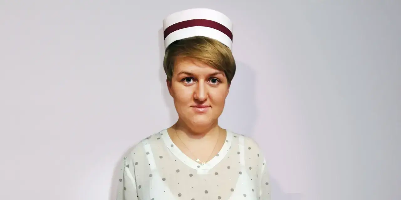Kobieta w czepku pielęgniarskim, z delikatnym uśmiechem. Może to być przyszła mama, która właśnie przygotowuje swój