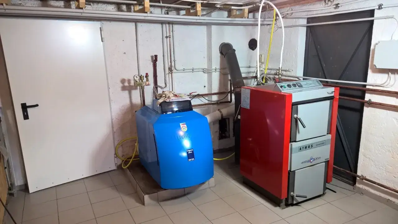 Heizungsanlage mit zwei Kesseln, ein blauer Buderus und ein roter Atmos. Holzvergaser Nachteile: Platzbedarf und Wartung.