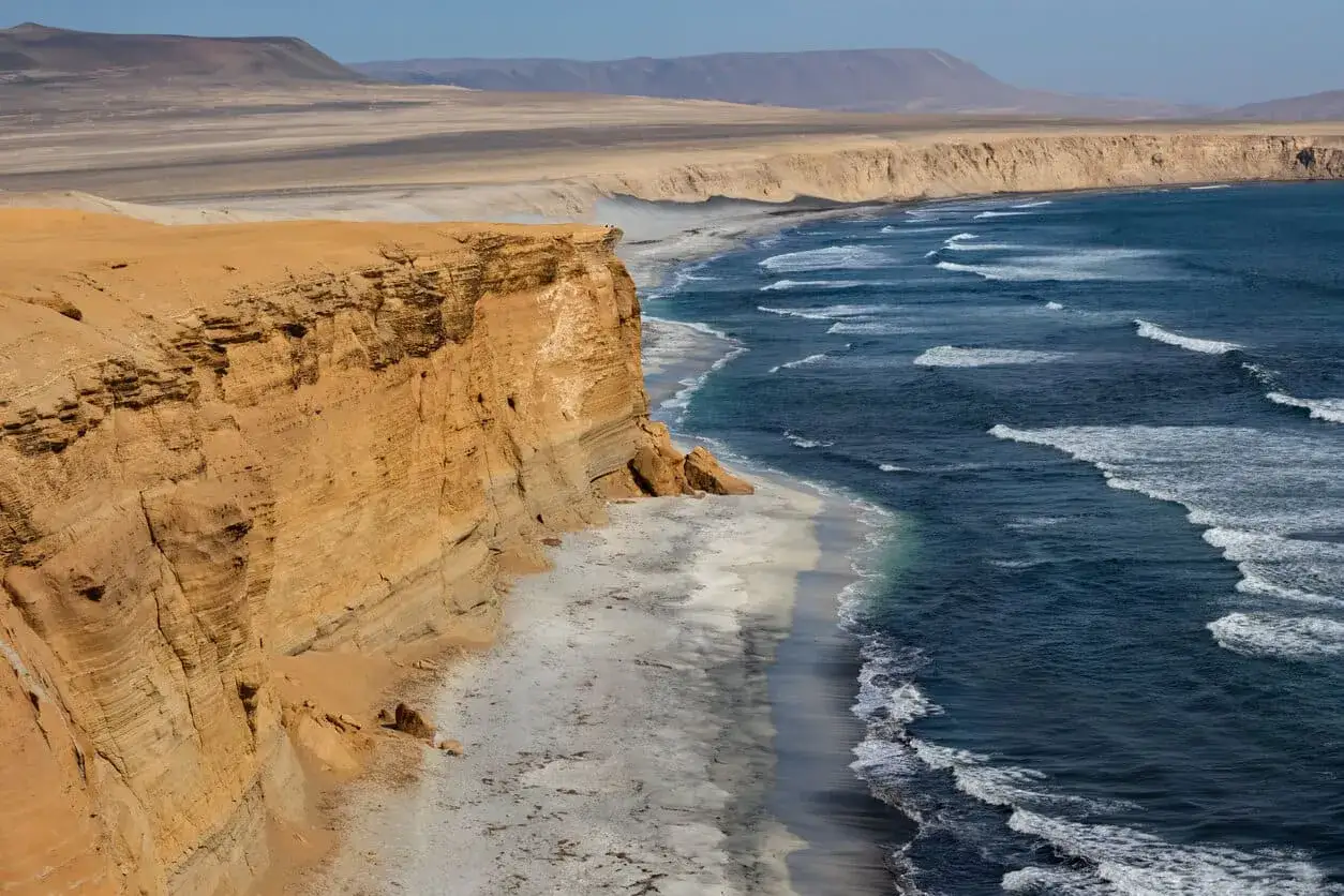 Steile Felsklippen treffen auf das Meer. Das Peru Wetter im Dezember ist hier sonnig und die Wellen brechen an der Küste.
