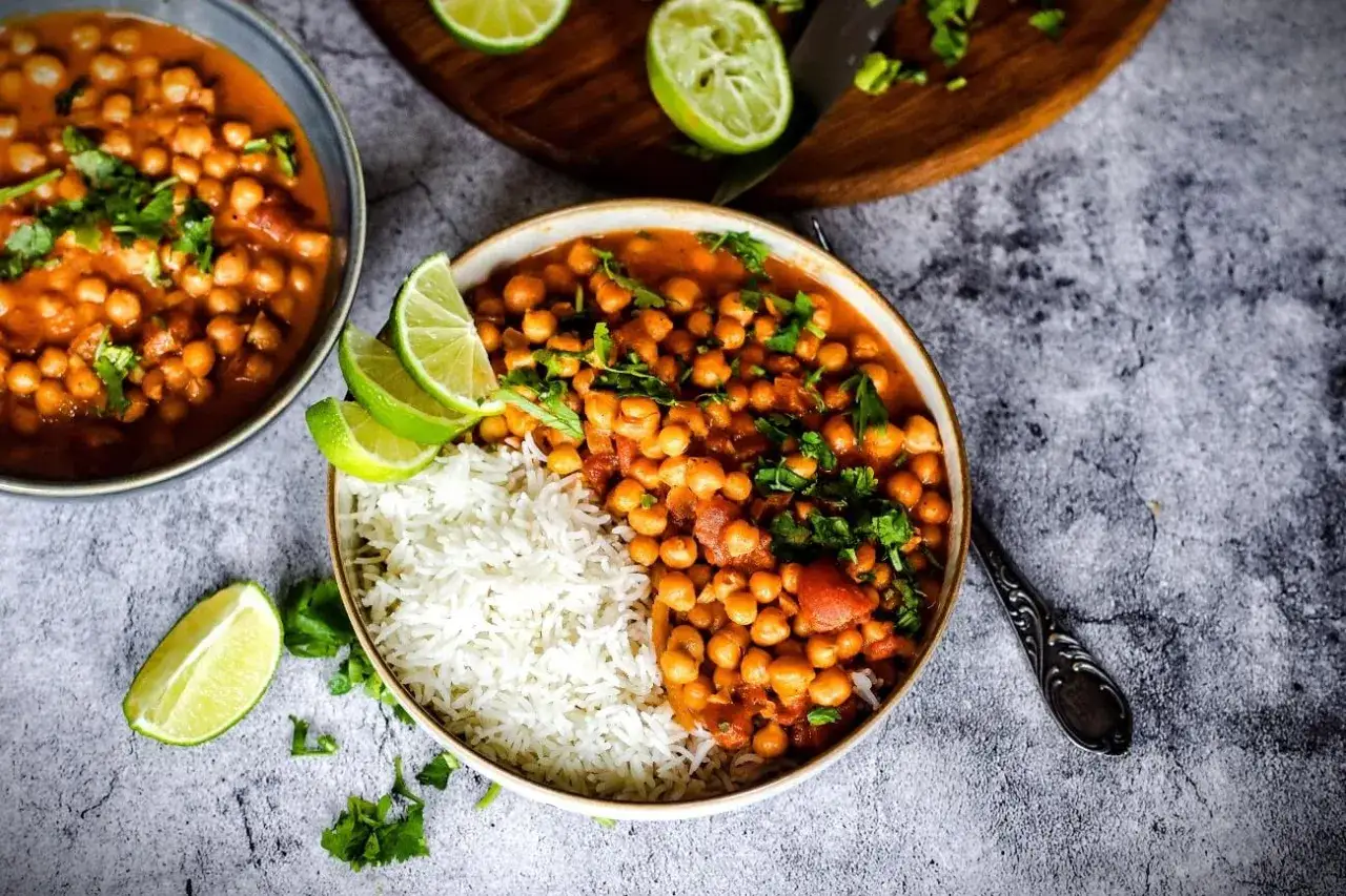 Zwei Schalen mit Kichererbsen-Curry und Reis, garniert mit Limettenspalten und Koriander. Perfekt zum Kichererbsen Curry einfrieren.