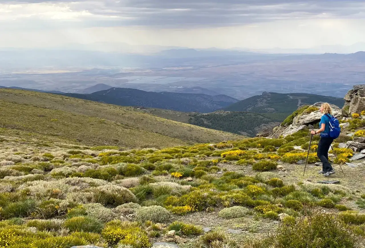 Senderista en el pico m&aacute;s alto de Almer&iacute;a, disfrutando de un paisaje monta&ntilde;oso con vegetaci&oacute;n y vistas lejanas.