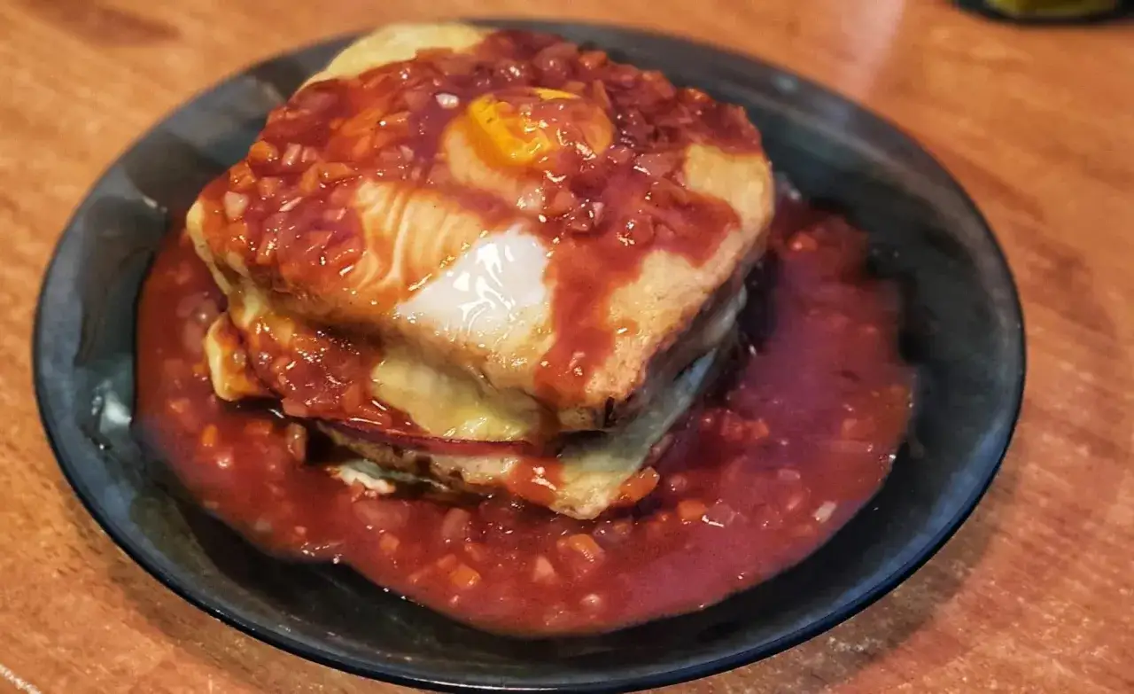En gener&ouml;s portion portugisisk mat: en sm&ouml;rg&aring;s t&auml;ckt med ost, en stekt &auml;gg och en smakrik tomats&aring;s.