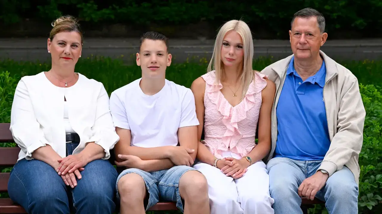 Familie sitzt auf einer Bank. Die Frau denkt über den mental load nach, während die Kinder und der Mann entspannt wirken.