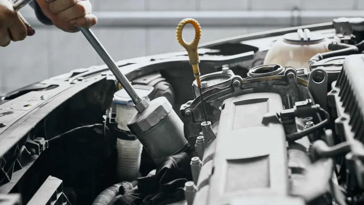 Mechanik sprawdza poziom oleju, co może być jednym z objawów uszkodzonej pompy oleju.