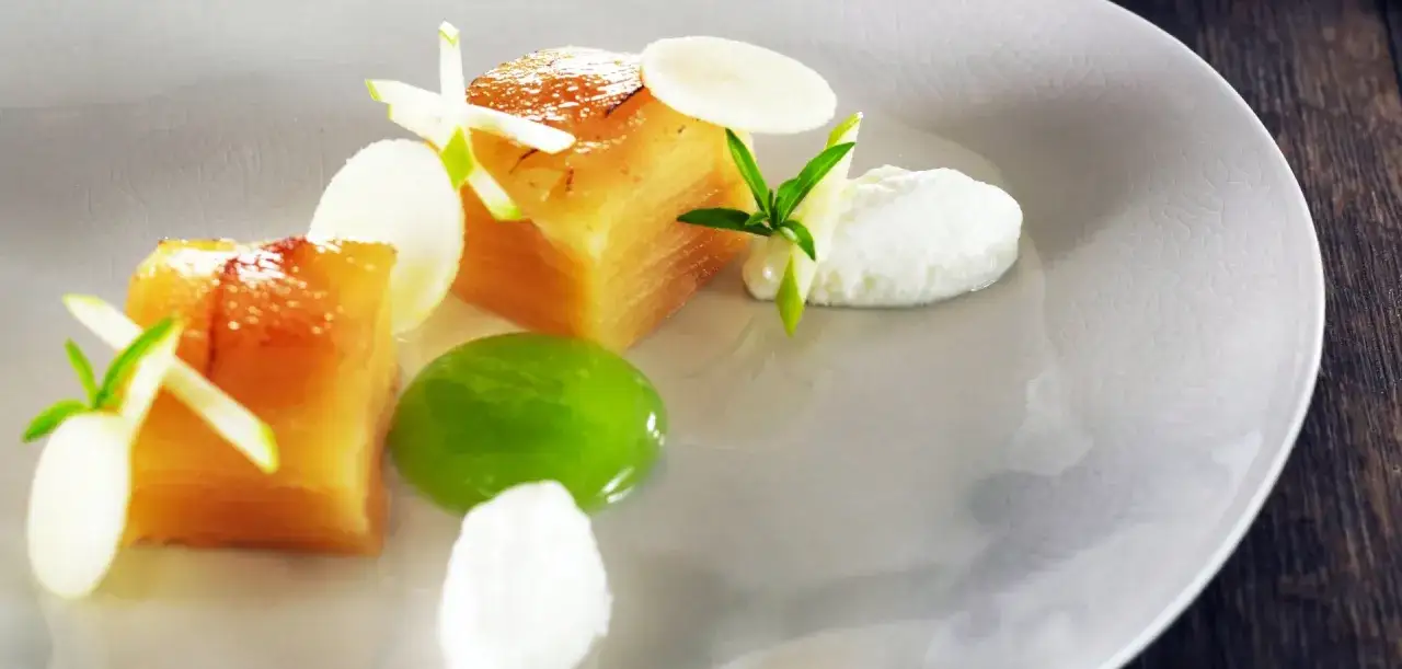 Un d&eacute;licieux dessert fevrier : cubes de fruits caram&eacute;lis&eacute;s, cr&egrave;me fouett&eacute;e, gel&eacute;e verte et fines lamelles de pomme sur une assiette textur&eacute;e.