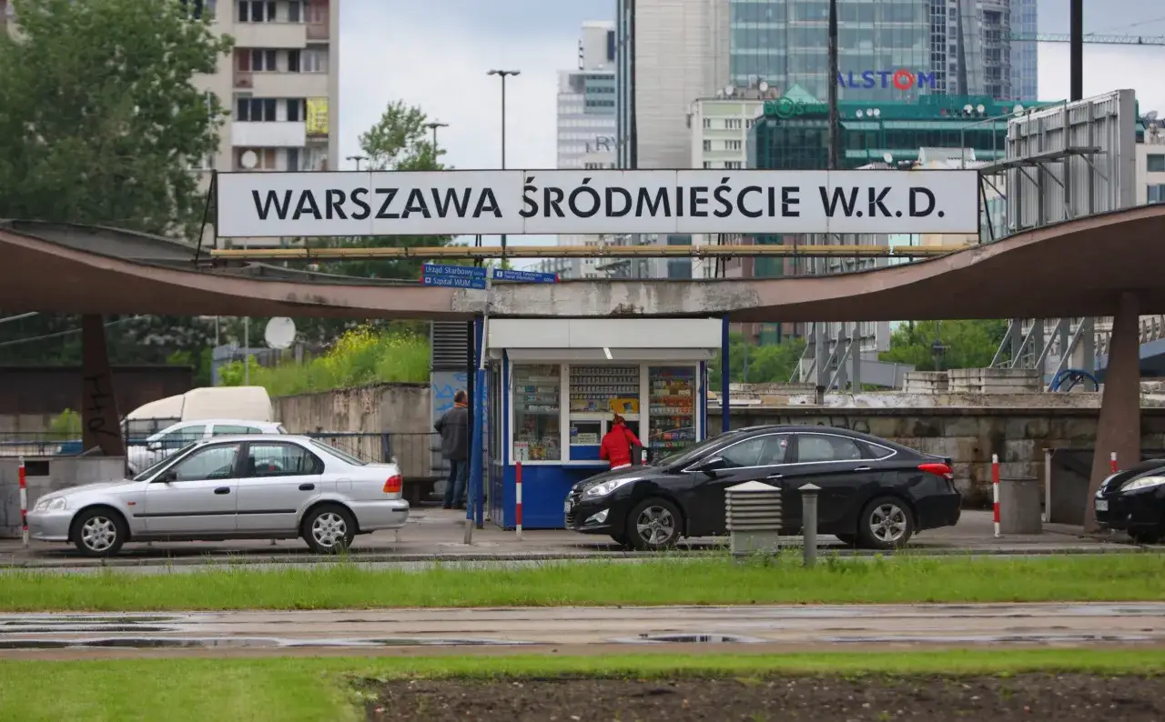 Warszawska Kolej Dojazdowa (WKD) przy stacji Warszawa Śródmieście. Dwa samochody stoją przed budynkiem stacji.