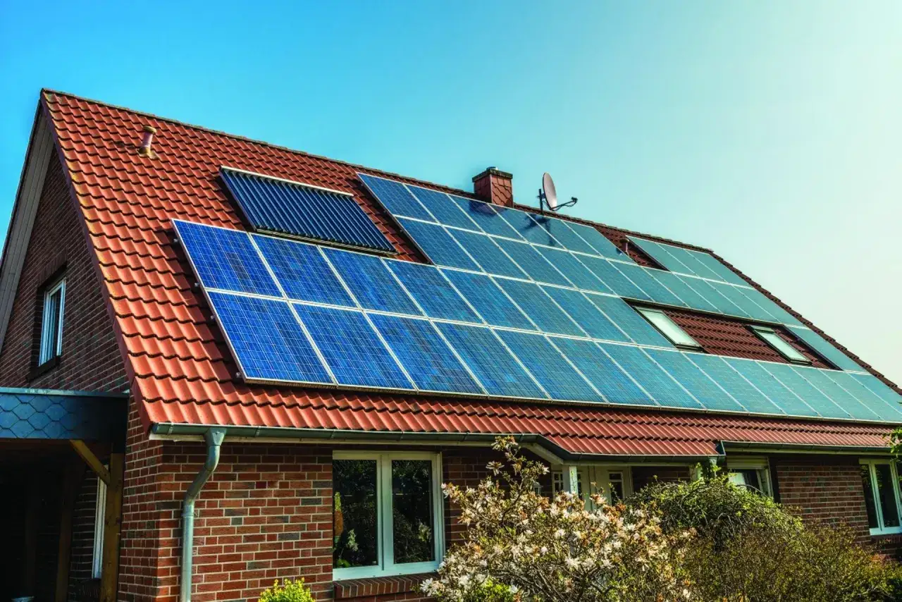 Nowoczesna instalacja fotowoltaiczna na dachu domu z czerwonej cegły. Panele słoneczne zbierają energię, zapewniając ekologiczne zasilanie.