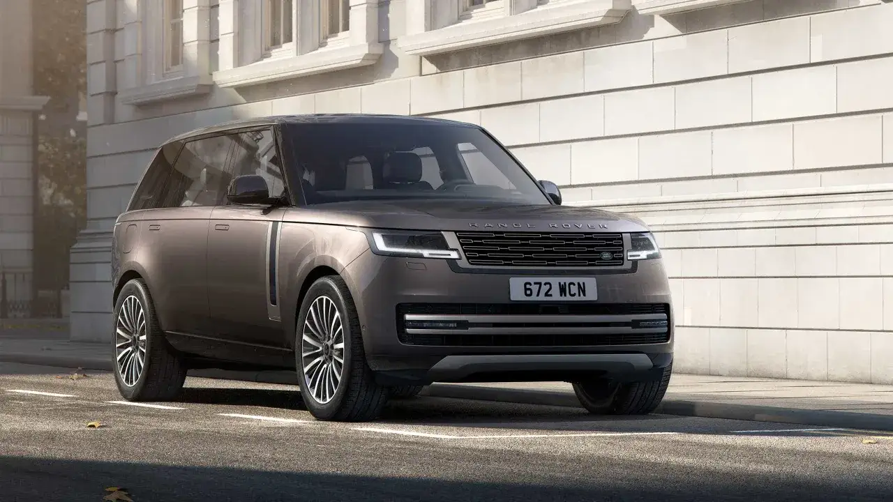 Elegancki Range Rover 2025 w kolorze brązowym, zaparkowany przed nowoczesnym budynkiem.