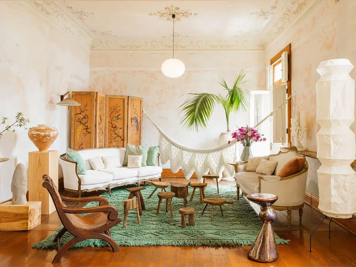 Sal&oacute;n con estilo boho decoraci&oacute;n, sof&aacute;s blancos, hamaca, plantas y pantalla decorativa.