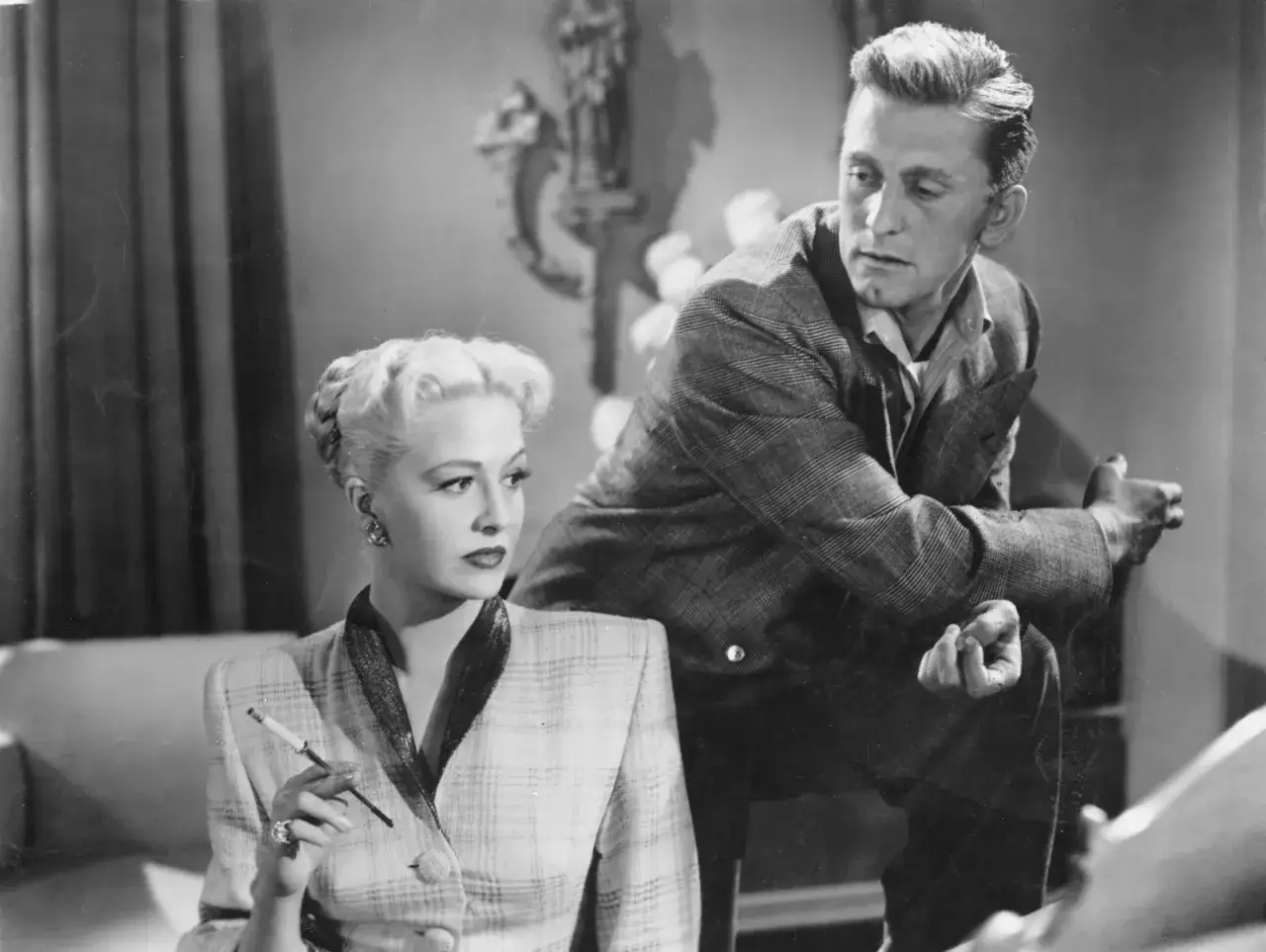Kobieta z papierosem i mężczyzna w kratowanej marynarce, scena z jednego z **kirk douglas filmy**.
