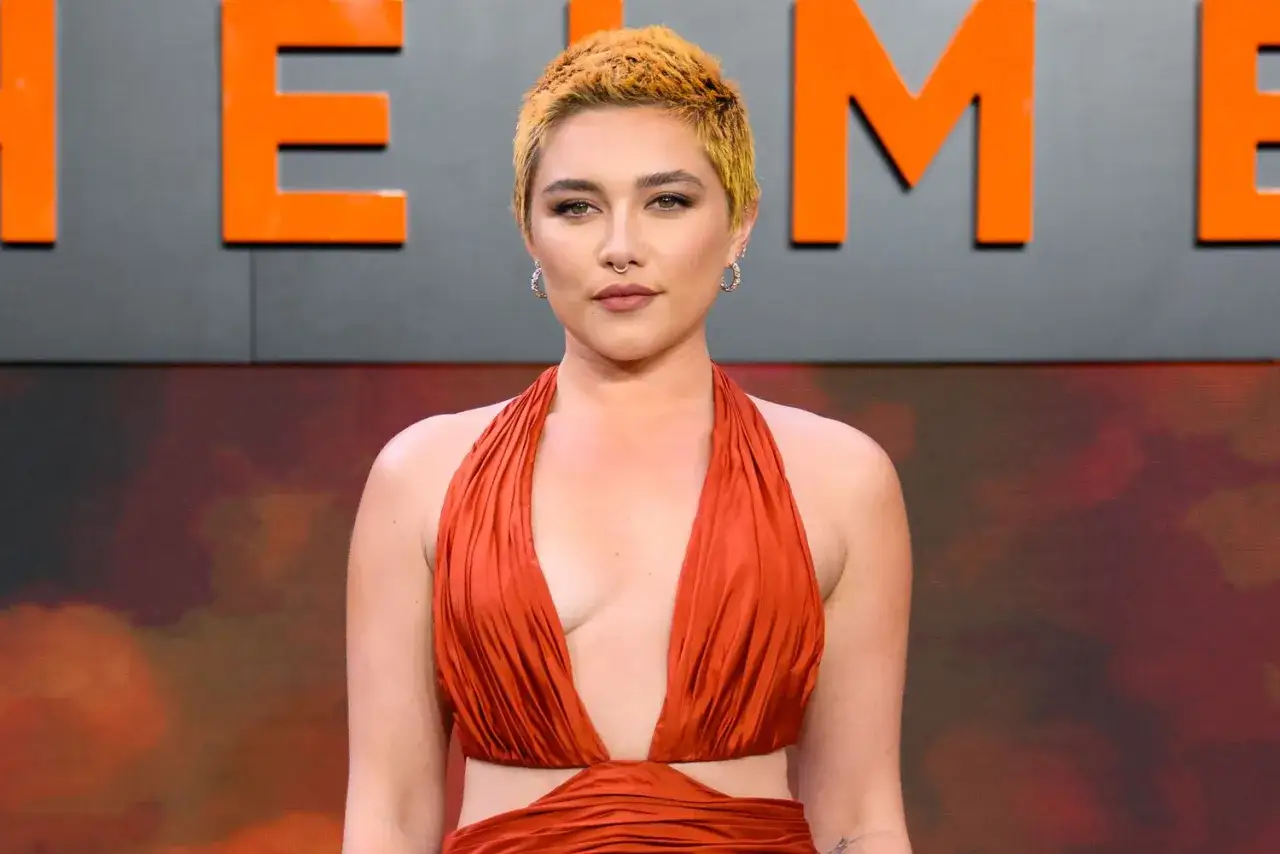 Florence Pugh w pomarańczowej sukni, gwiazda wielu filmów, prezentuje się z pewnością siebie.