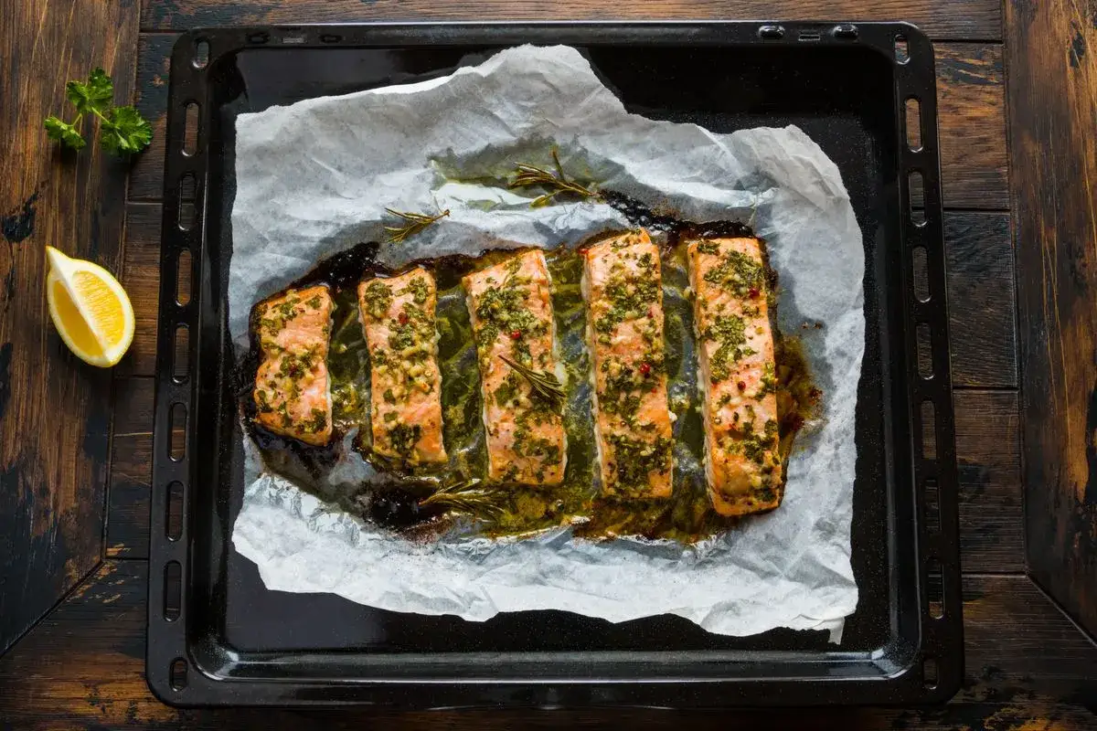 Sei filetti di salmone al cartoccio, conditi con erbe aromatiche e spezie, pronti per essere gustati.