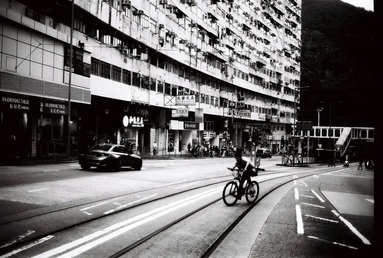 A cyclist rides along tram tracks in a gritty urban scene, captured with the distinct look of Rollei Retro 400s film.