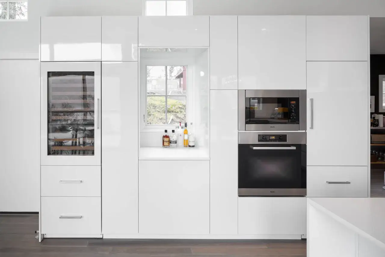 Cucina moderna bianca con elettrodomestici integrati e una porta finestra che illumina l'ambiente.