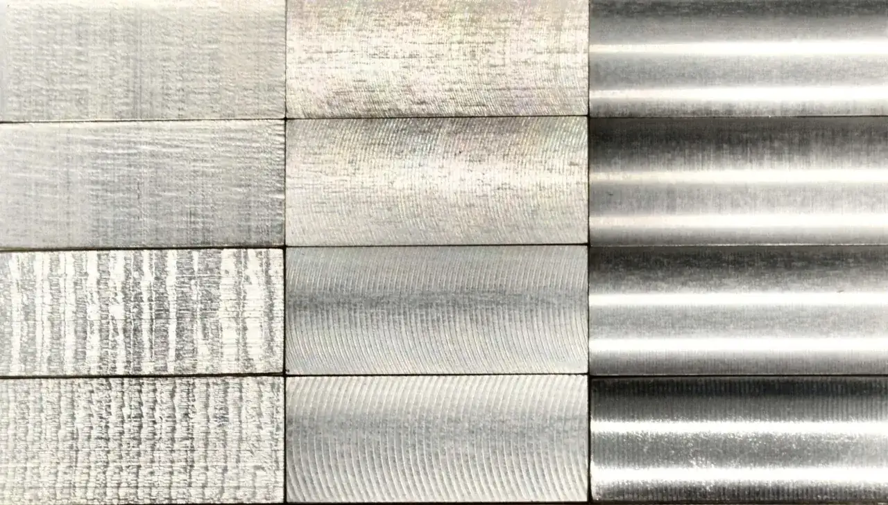 Rzędy pr&oacute;bek metalowych z r&oacute;żnymi wzorcami chropowatości: od drobnych linii po gładkie, lustrzane powierzchnie.