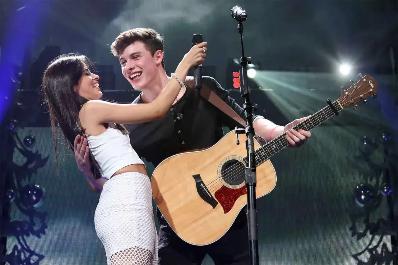 Camila Cabello i Shawn Mendes śmieją się na scenie, gdy Shawn gra na gitarze.
