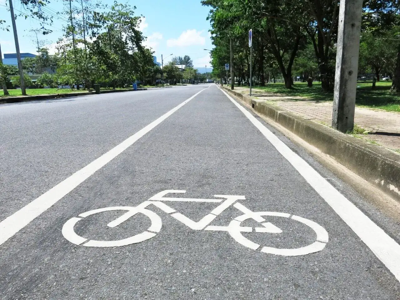 Eine weiße Fahrrad-Symbolik auf dem Asphalt kennzeichnet den Radweg.