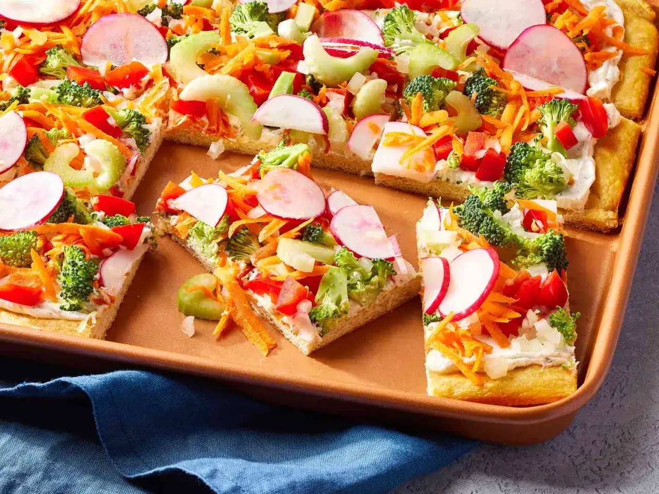 Kolorowa pizza z mnóstwem warzyw – czy domowa pizza jest zdrowa? Ten przepis udowadnia, że tak! Brokuły, marchewka, rzodkiewka, pomidory i ogórek na chrupiącym spodzie.