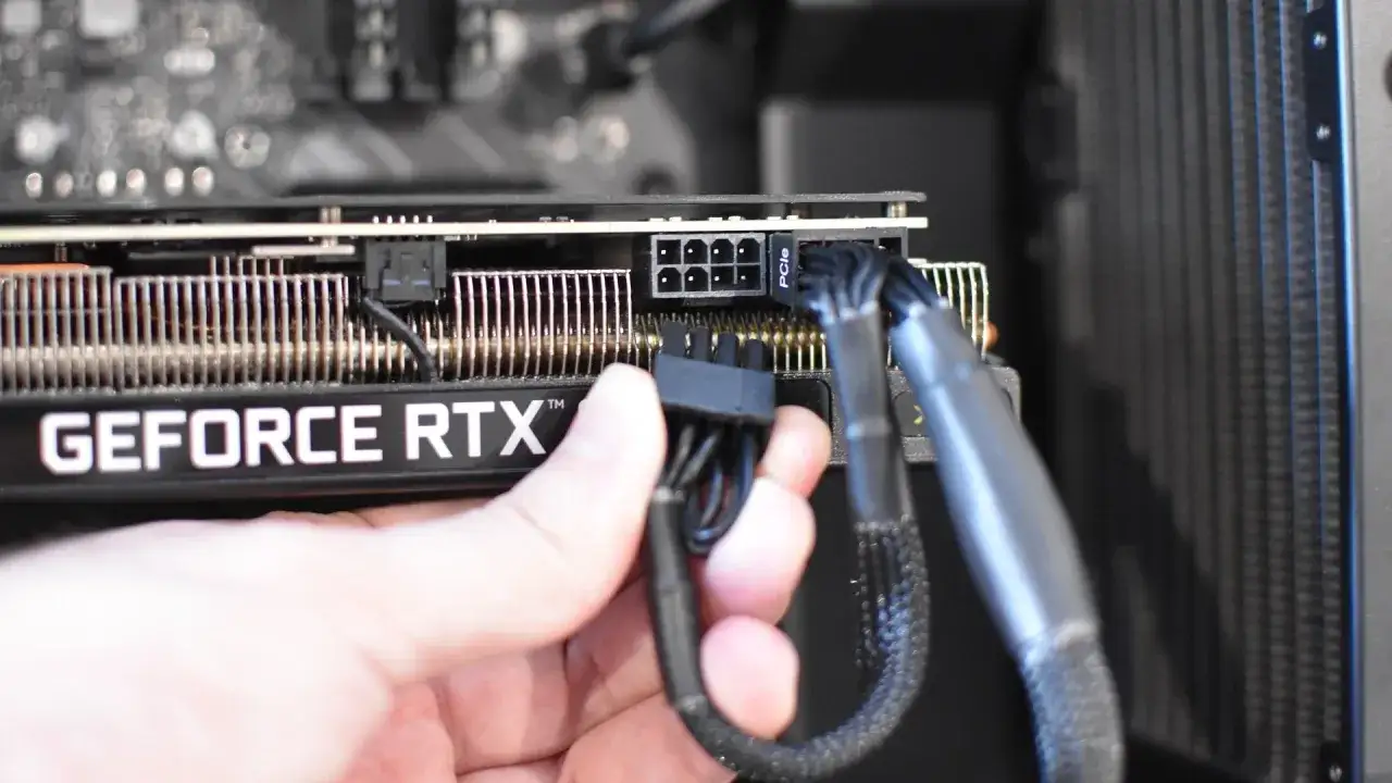 Main d'une personne connectant un câble d'alimentation PCIe à une carte graphique GeForce RTX. Guide pour comment installer une carte graphique.