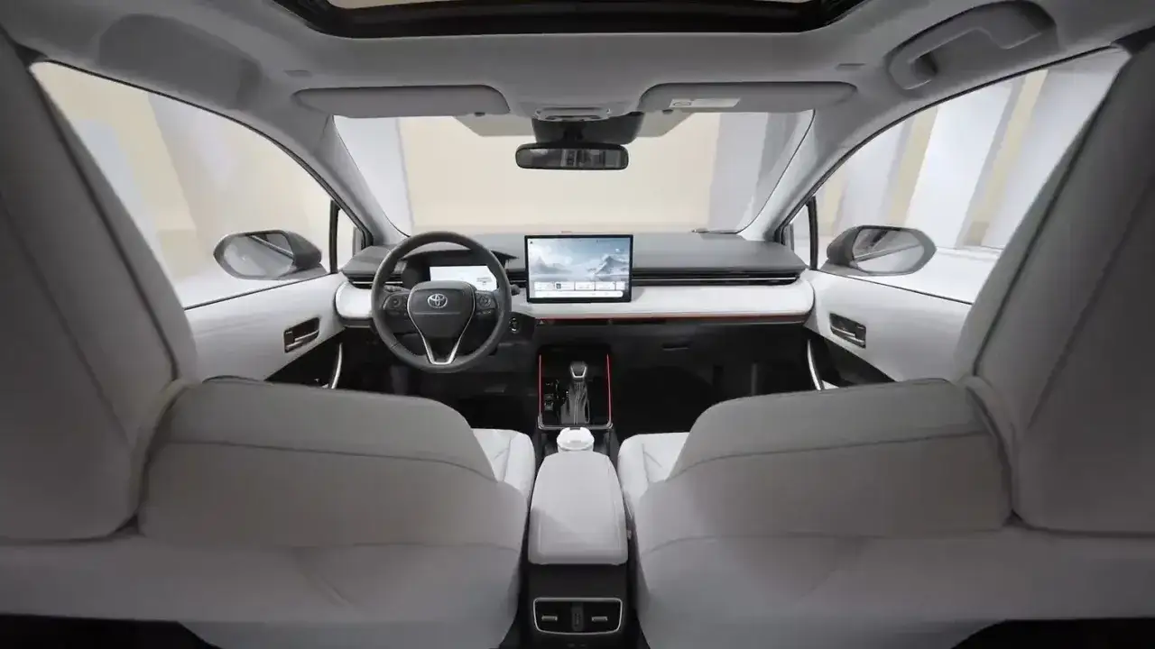 Wnętrze nowoczesnej **toyota corolla sedan** z dużym ekranem multimedialnym i jasnymi siedzeniami.