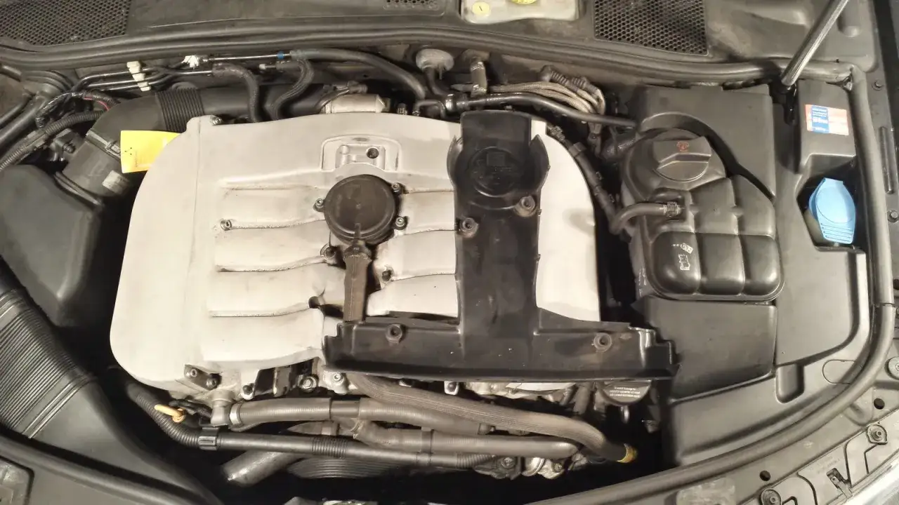 Der Motorraum eines Autos mit einem silbernen w8 Motor, Kühlmittelbehälter und anderen Komponenten.