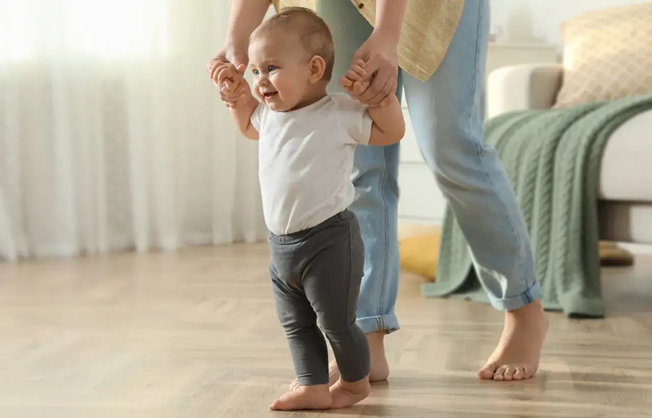 Ein Baby lernt laufen, gehalten von einer Person. Die ersten Schritte sind aufregend!