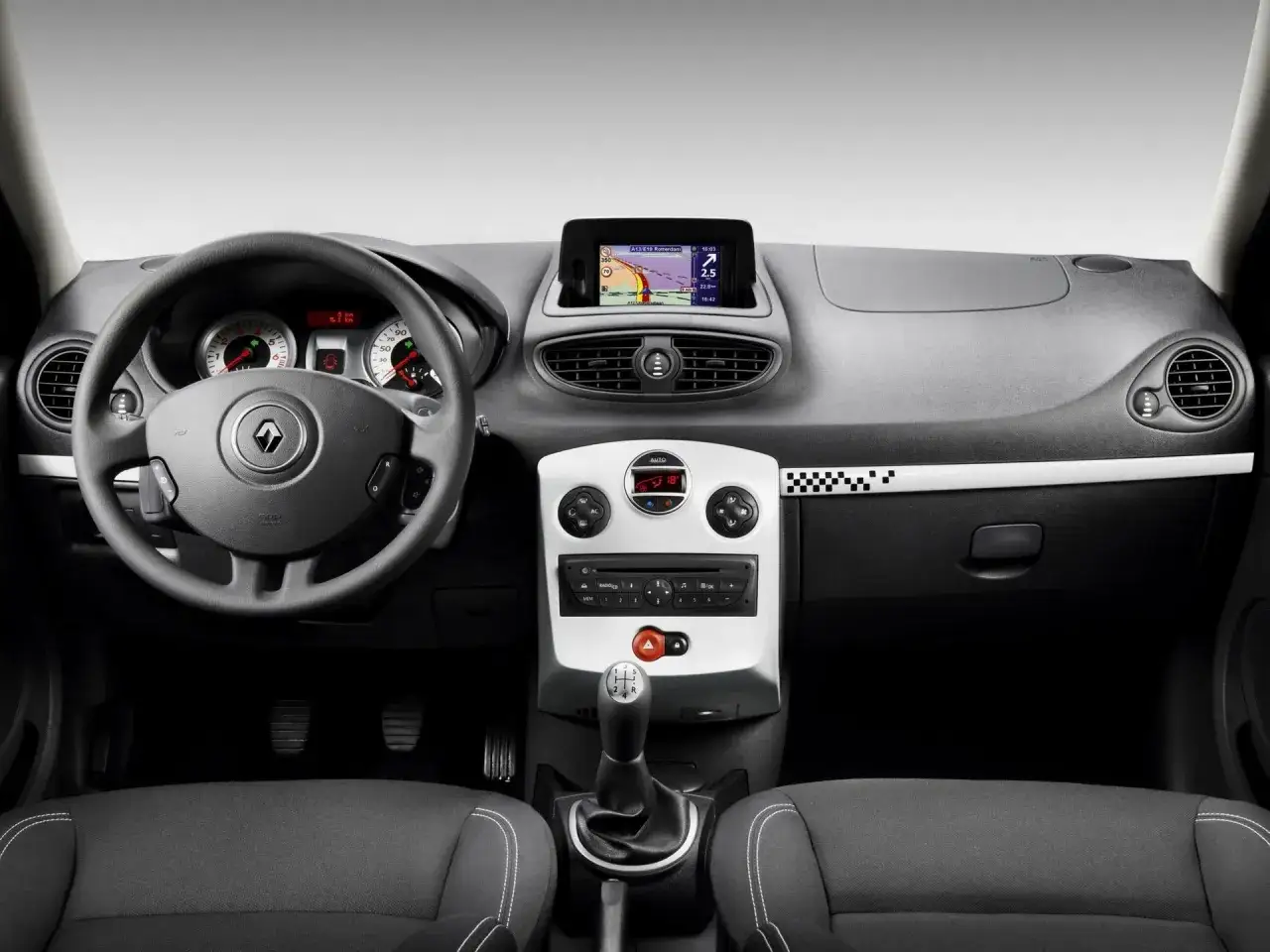 Wnętrze Renault Clio 3 z nawigacją GPS, radiem i manualną skrzynią biegów.