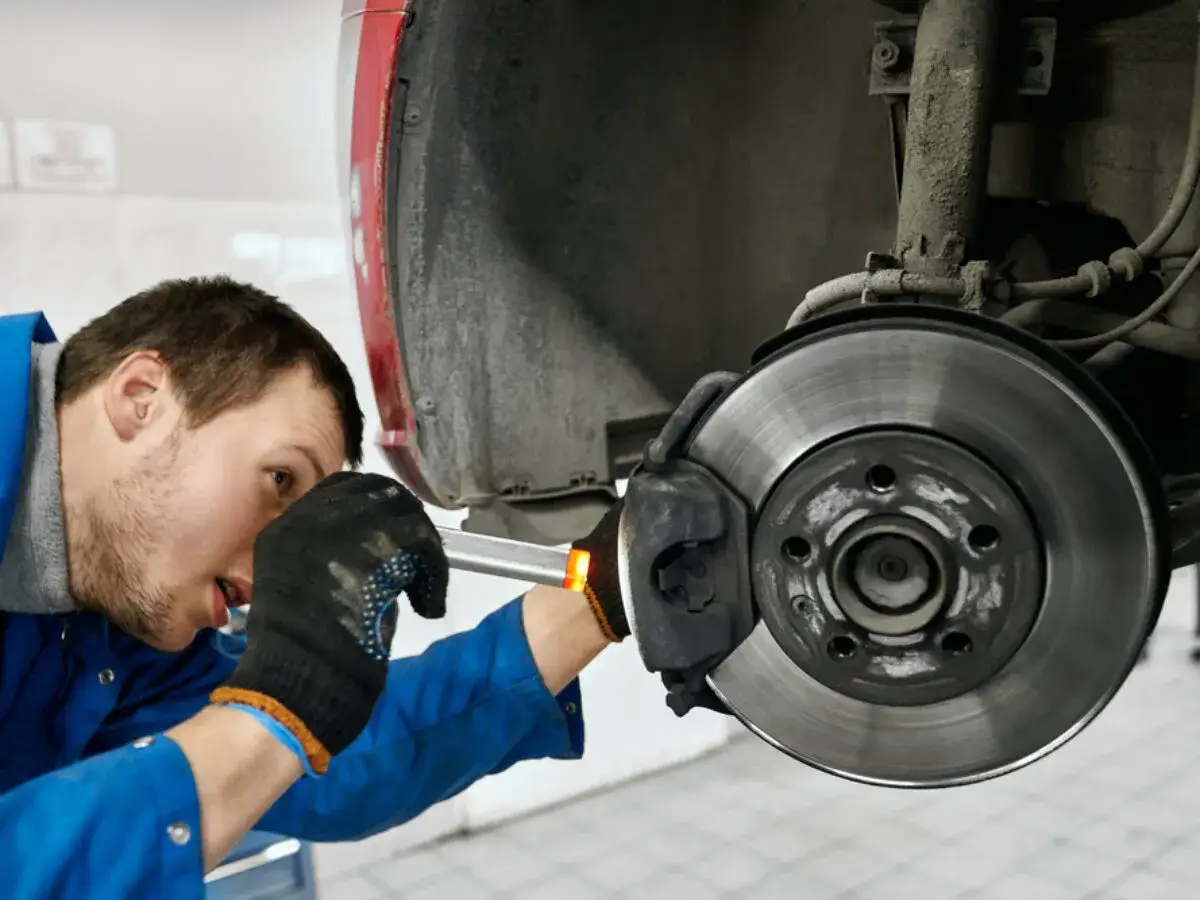 Mechaniker prüft Bremse, um zu beheben, dass das Lenkrad ruckelt beim Bremsen.
