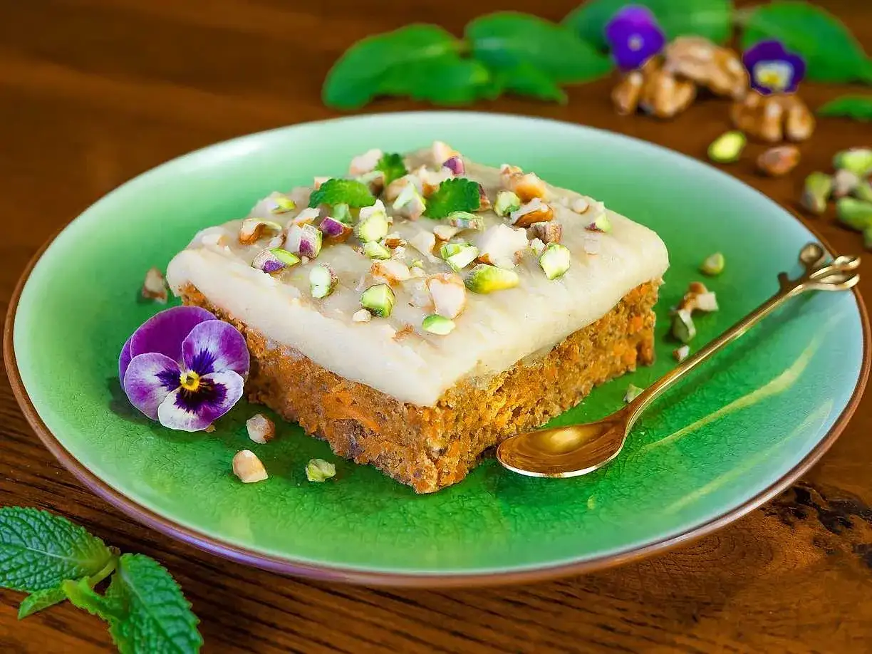 En saftig bit morotskaka med krämig frosting, toppad med pistagenötter och mynta. Perfekt för ett fika-recept!