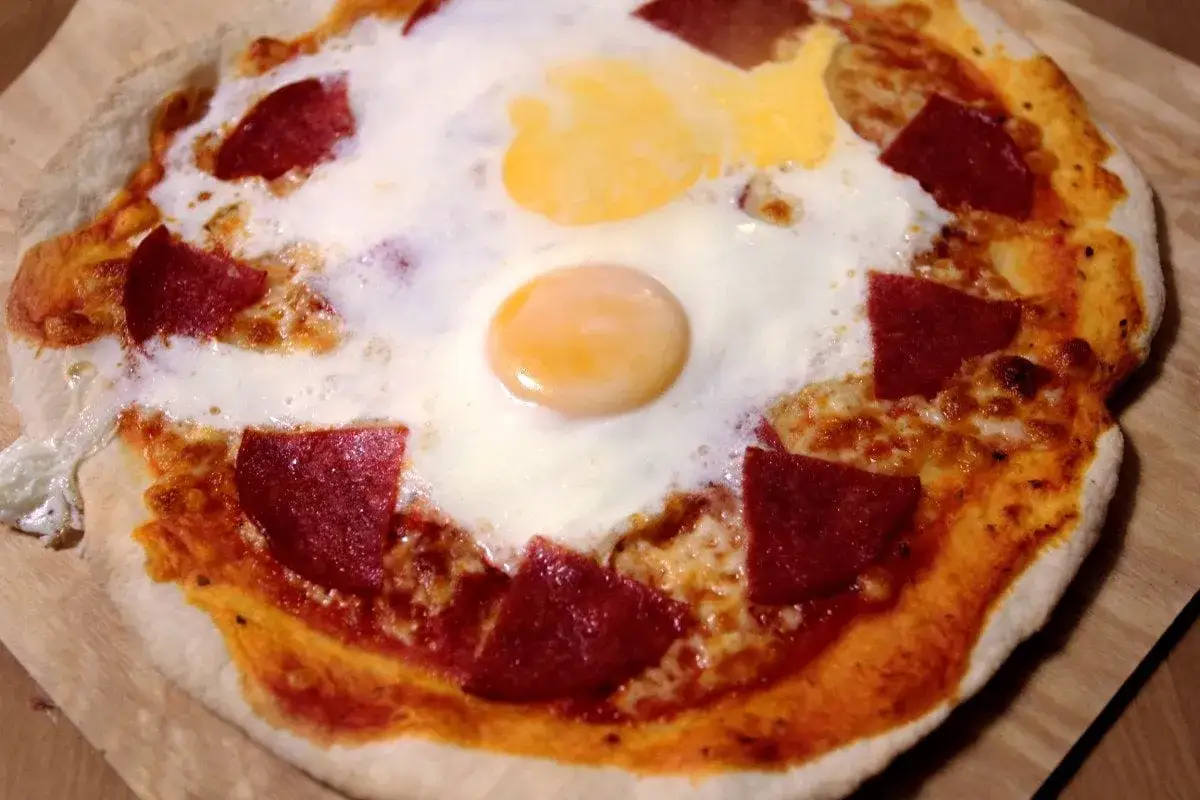 Pyszna pizza z jajkiem sadzonym i salami. Idealna na śniadanie lub szybki obiad.