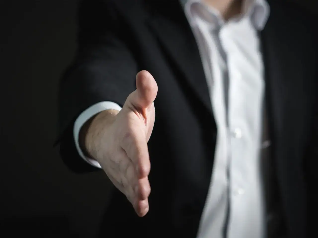 Ein Geschäftsmann im Anzug streckt die Hand aus, um sich vorzustellen.