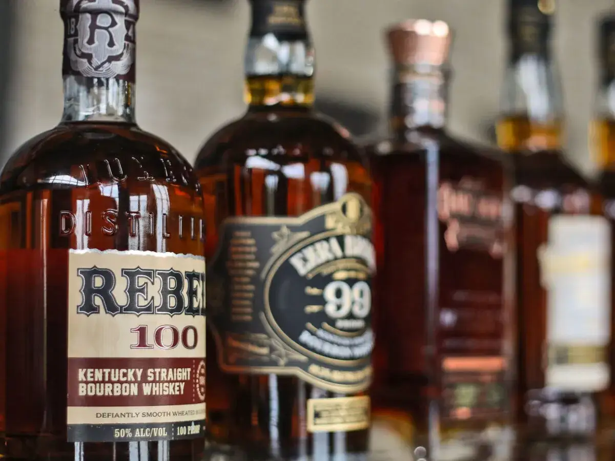 Mehrere Flaschen Bourbon Whiskey nebeneinander. Die Unterschiede im Etikettendesign und der Farbe des Whiskeys sind erkennbar.