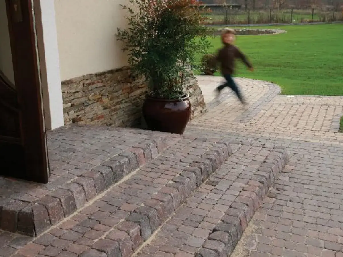 Schody z kostki brukowej, idealne do ogrodu. Dziecko biegnie po ścieżce, pokazując, jak zrobić fugę.