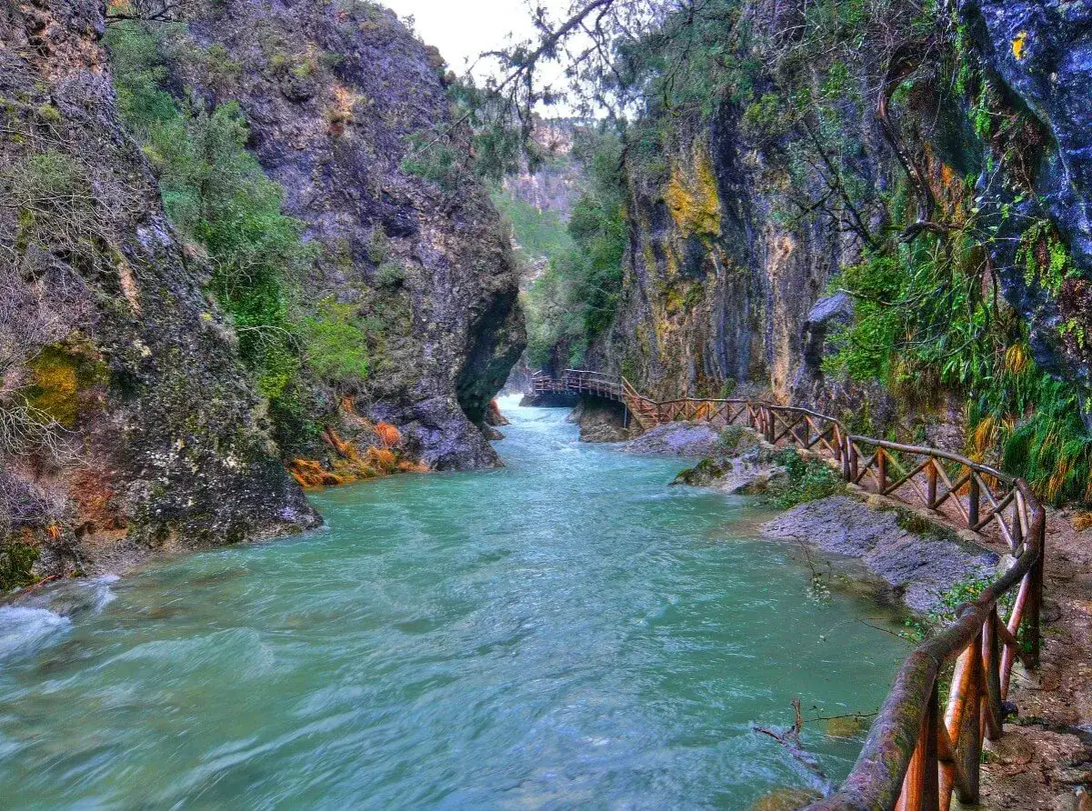 Un r&iacute;o turquesa serpentea entre ca&ntilde;ones rocosos, con un sendero de madera que acompa&ntilde;a el recorrido. Ideales para rutas senderismo Ja&eacute;n.