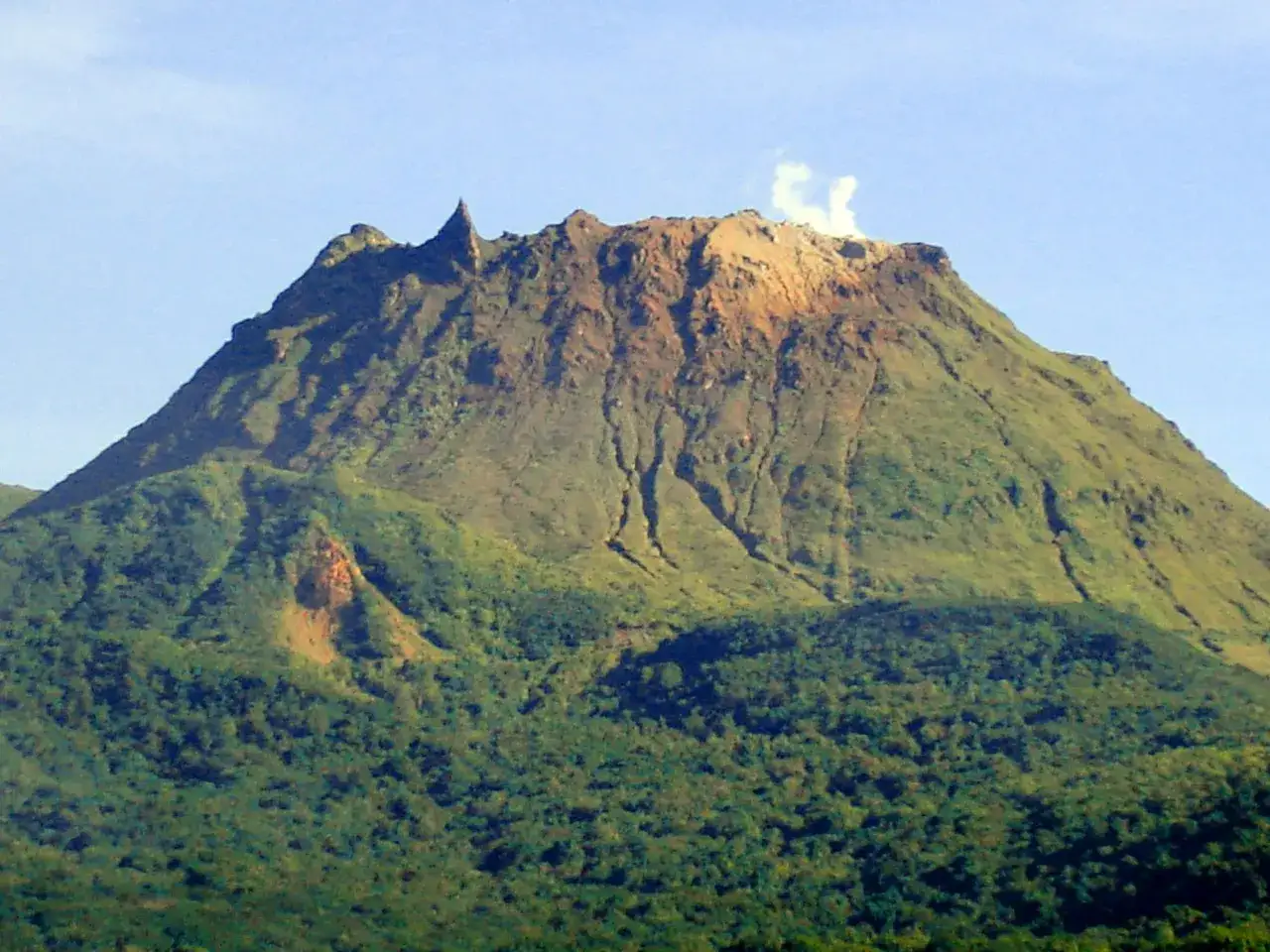 La Soufri&egrave;re, un volcan verdoyant, crache une fum&eacute;e blanche. Ses flancs sont couverts d'une v&eacute;g&eacute;tation dense.